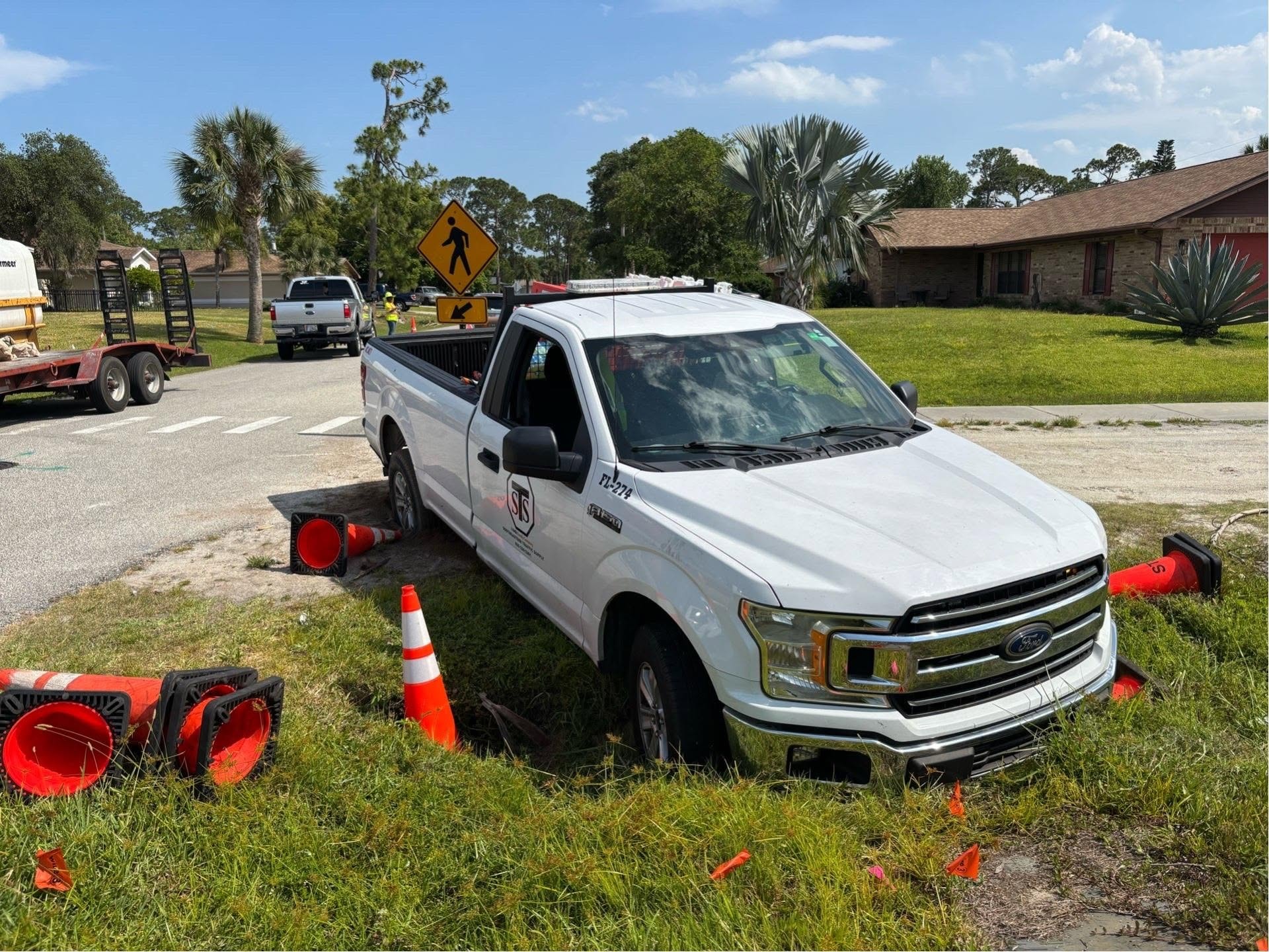 White Ford F-150 stuck off the roadway surrounded by construction cones requiring recovery