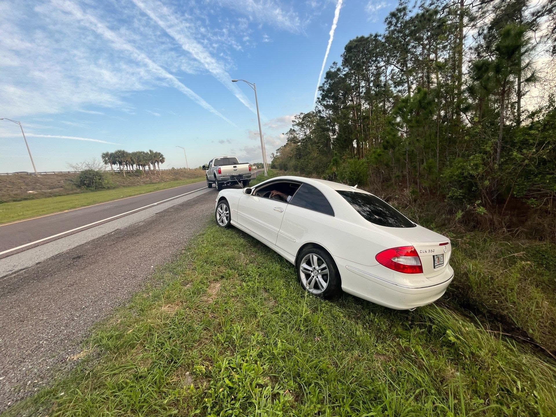 White Mercedes CLK off the roadway shoulder with JF Drives recovery truck positioned on the road ahead
